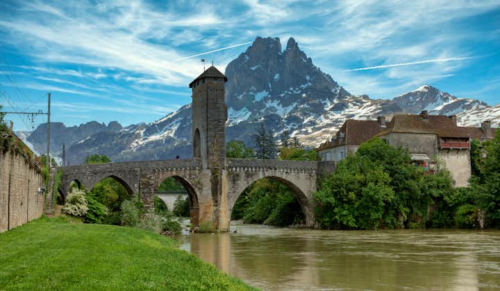 Photo of a bridge over river Gave de Pau in Orthez and Pic du midi Ossau ,France.