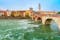 photo of Ancient Roman bridge Ponte Pietra and the River Adige in cloudy summer day, Duomo tower in background, Verona, Italy .