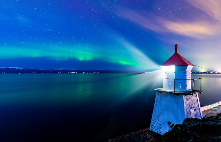 A light house in Trondheim with a sky with northern lights in the background.