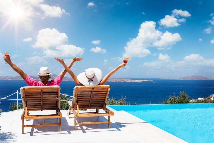 Photo of couple sitting on sunchairs enjoying the sun during their summer holidays in Mykonos.