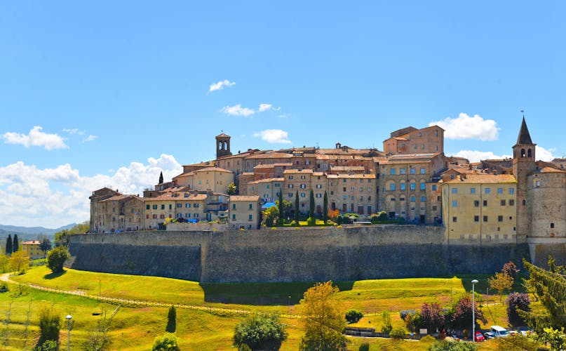 photo of view of landscape with Anghiari italian medieval village city walls on green hill and blue sky in background. Arezzo, Italy.