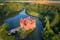 Photo of aerial view of bizarre water castle Cervena Lhota, red château standing at the middle of a lake on a rocky island, Czech Republic.
