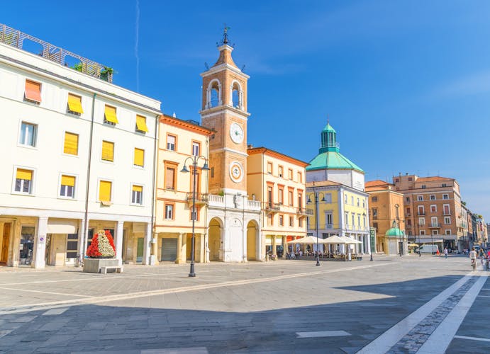 Photo of Piazza Tre Martiri Three Martyrs square with traditional buildings with clock and bell tower in old historical touristic city centre Rimini with blue sky background.