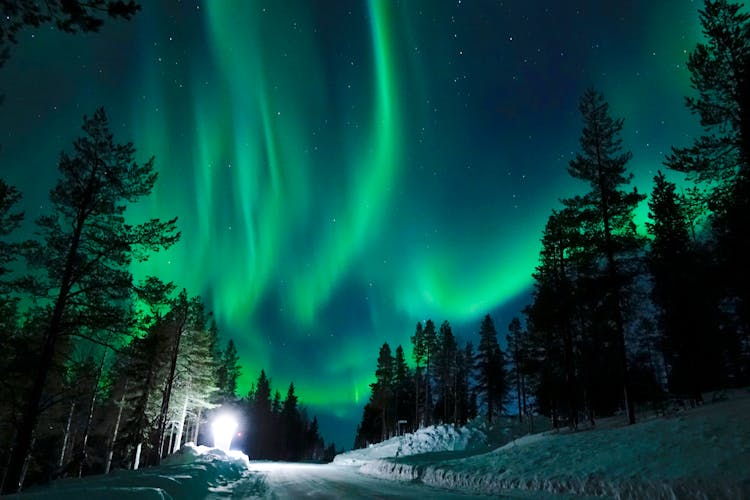 Photo of the northern lights appear above the idyllic Scandinavian countryside in the winter, Rovaniemi.
