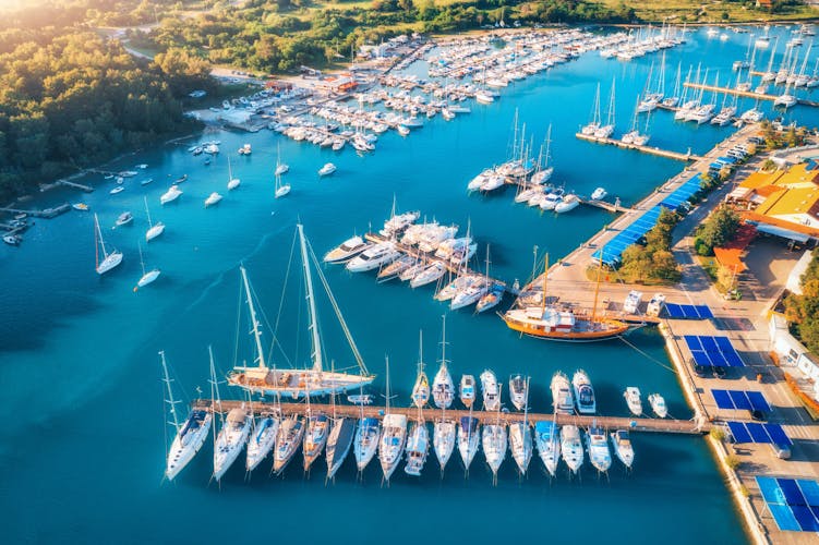 Photo of aerial view of boats and luxury yachts in dock at sunset in summer in Pula, Croatia.