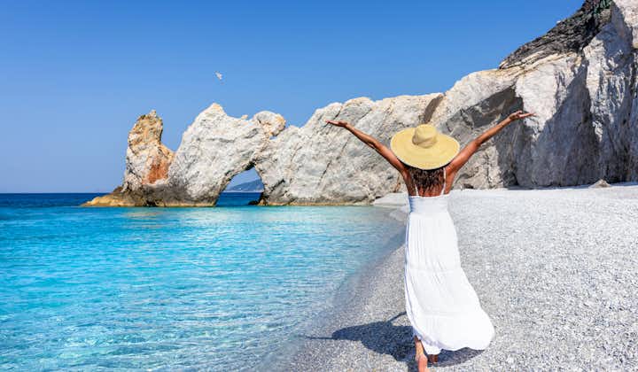 Photo of tourist woman in a white summer dress enjoys the beautiful beach of Lalaria, Skiathos island, Greece.