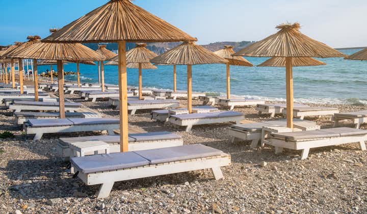 Photo of beach with sun umbrellas and sunbeds in town Bar in Montenegro on Adriatic sea.