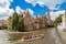 Photo of canal in Bruges and famous Belfry tower on the background in a beautiful summer day, Belgium.