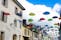 Photo of Colorful umbrellas in the blue sky above old street in Carouge town, neighborhood of Geneva, Switzerland, popular tourist traveling destination.