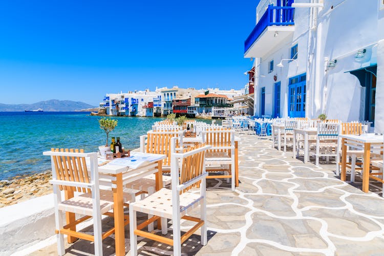 Photo of chairs with tables in typical Greek tavern in Little Venice part of Mykonos town, Mykonos island, Greece.