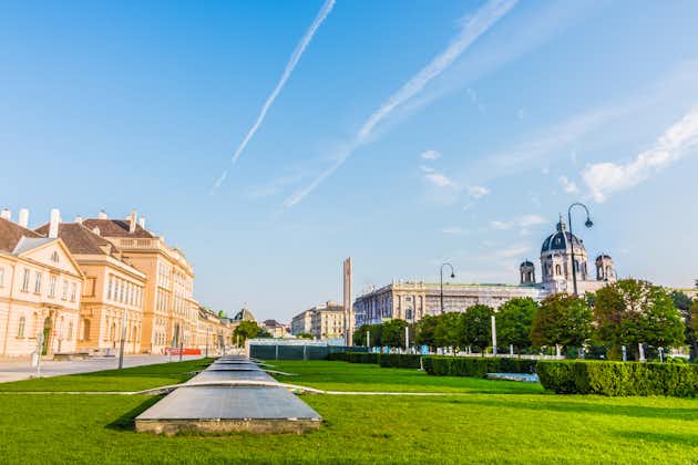 Photo of beautiful view of famous Museums Quartier and Naturhistorisches Museum (Natural History Museum) with green grass of park, airplane track in blue sky and metro airshaft. Landmark of Vienna, Austria.