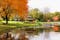 Photo of beautiful autumn landscape with colorful trees around the pond and wooden gazebo in Middleton Park, Leeds, United Kingdom.