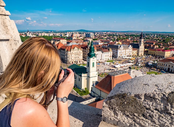 Woman tourist taking pictures of Oradea city main square.