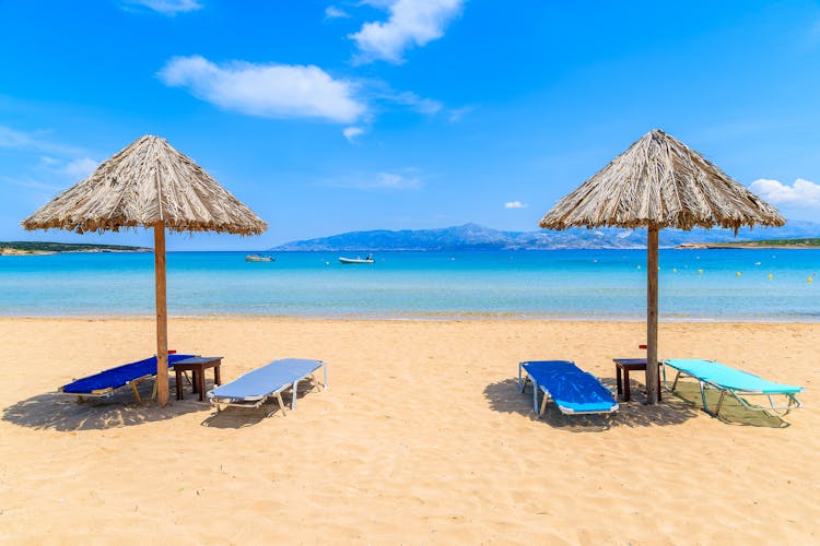 Photo of umbrellas with sunbeds on beautiful sandy Santa Maria beach with turquoise sea water, Parikia , Paros island, Greece