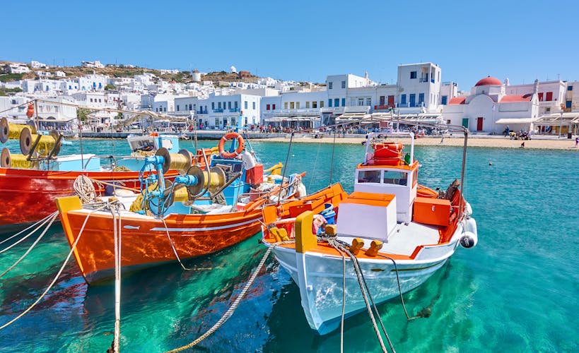 Photo of harbour with wooden fishing boats in Chora town on sunny summer day, Mykonos island, Greece.