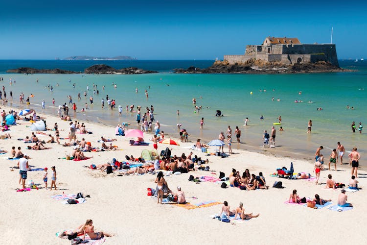 Crowded sandy beach at Saint Malo on a hot summer day with clear blue skies.