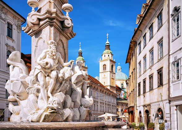 Photo of Fragment of Robba fountain in the historical center of Ljubljana, Slovenia. Ljubljana Cathedral on the background.