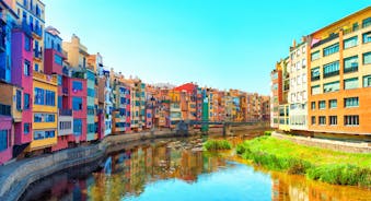 Photo of colorful yellow and orange houses and Eiffel Bridge, Old fish stalls, reflected in water river Onyar, in Girona, Catalonia, Spain.