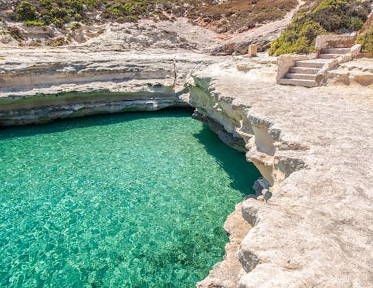 Photo of crystal clear turquoise water in blue lagoon of St. Peters pool  rocky beach at Malta.