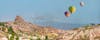 photo of hot air balloon flying over spectacular Uchisar castle and Pigeon valley in Cappadocia, Turkey.