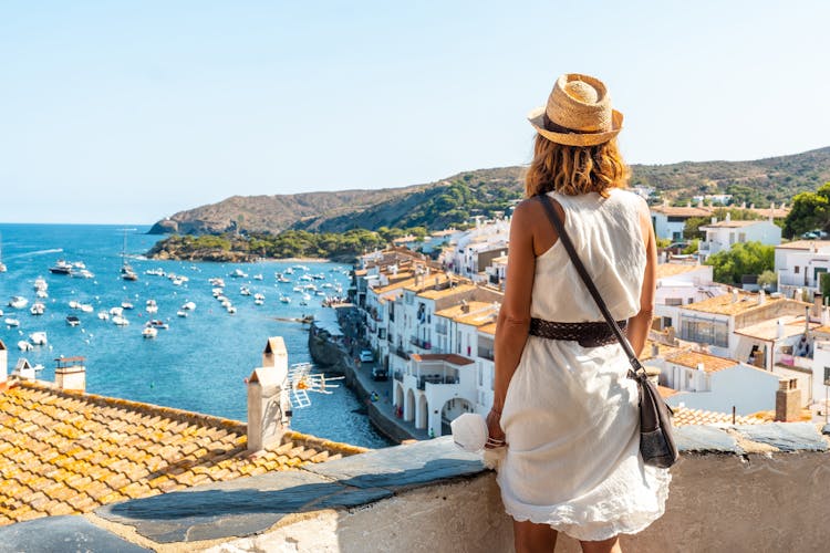 Photo of young woman on vacation looking at the city of Cadaques from a viewpoint, Costa Brava of Catalonia, Gerona.