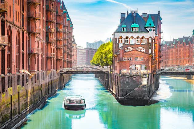 Photo of classic view of famous Hamburg Speicherstadt warehouse district with sightseeing tour boat on a sunny day in summer.