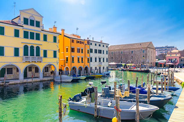 Photo of Chioggia with narrow water canal Vena with moored multicolored boats near wooden pier and colorful buildings, Italy.
