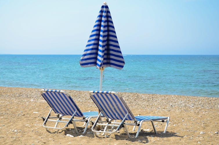 Photo of sandy beach with umbrella and sunbeds in Larnaca, Cyprus.