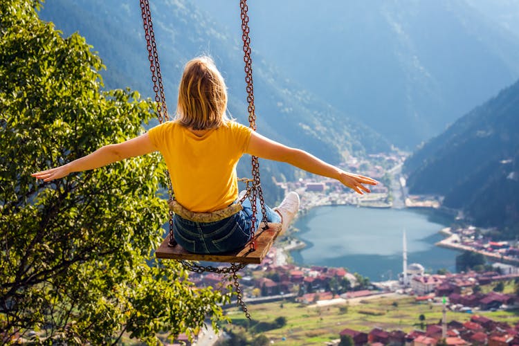 Photo of  female on a swing with the view of the mountain lake Uzungol, Trabzon, Turkey.