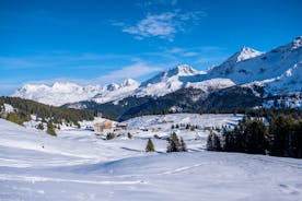 photo of beautiful snow capped mountains with Arosa village in France. Back country skier in the foreground leave their tracks in the deep snow.