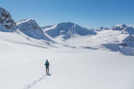 photo of beautiful snow capped mountains with Arosa village in France. Back country skier in the foreground leave their tracks in the deep snow.