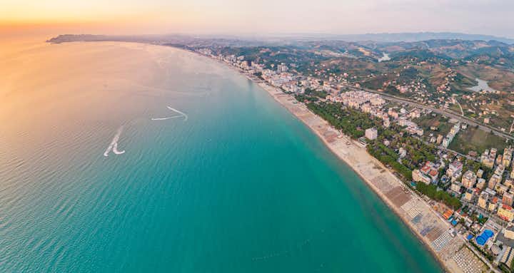 Photo of aerial view of the beautiful coastline with sandy beach of the Albanian town of Golem with the city of Durres in the background.