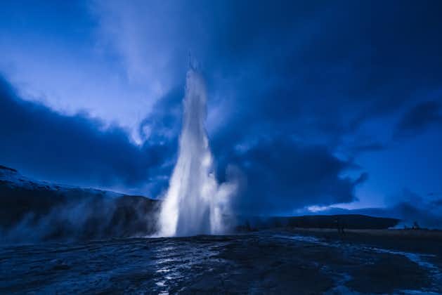 photo of eruption of strokkur geyser in Iceland. Winter cold colors, moon lighting through night the steam.