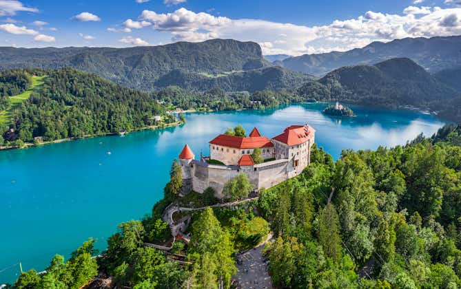 Aerial panoramic view of beautiful Bled Castle (Blejski Grad) with Lake Bled (Blejsko Jezero), the Church of the Assumption of Maria and Julian Alps at background on a nice summer day