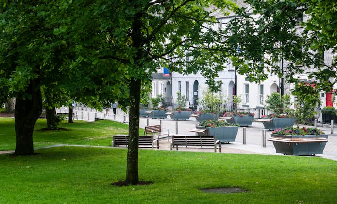 Photo of Eyre Square, Galway City on a quiet summer morning showing the surrounding flora and buildings.