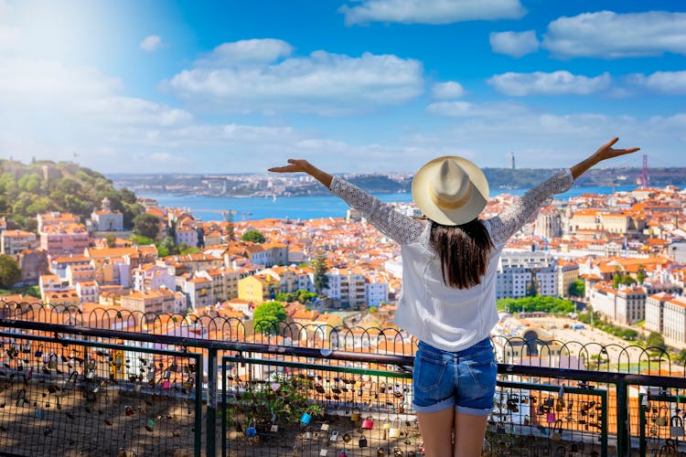 Photo of a happy tourist woman overlooks the colorful old town Alfama of Lisbon city, Portugal.