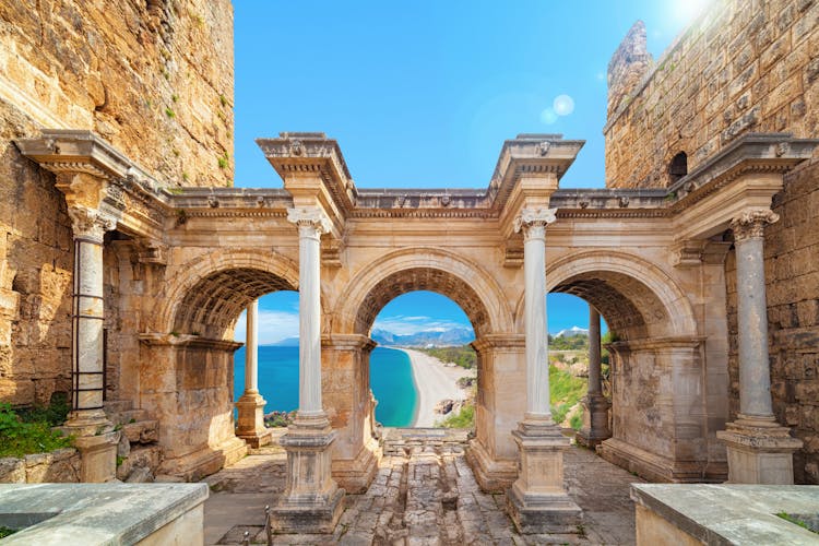 Photo of famous landmarks: Hadrian's Gate old town Kaleici district and Konyaalti beach in popular resort city Antalya, Turkey.