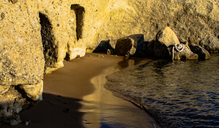 Photo of ancient inscription inside a cave with beautiful beach view near Pachaina, Milos, Greece.
