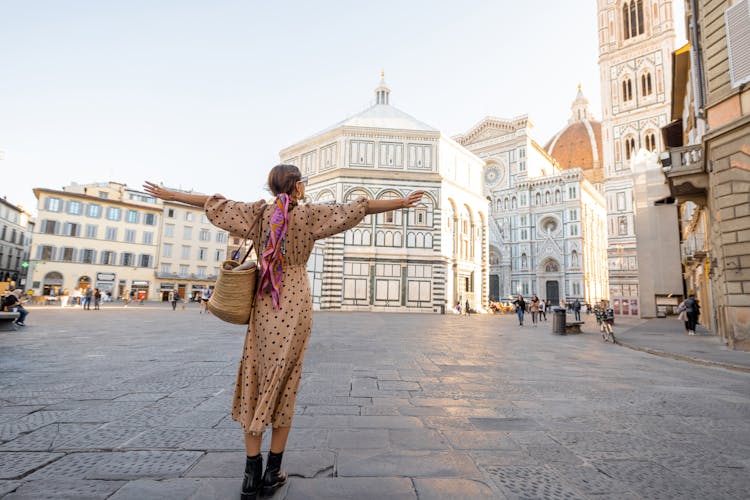 Photo of Woman enjoys beautiful view on famous Duomo cathedral in Florence, standing on empty cathedral square during morning time.