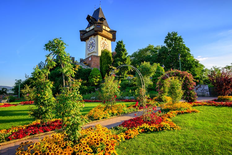 Photo of the medieval Clock tower Uhrturm in flower garden on Shlossberg hill, Graz.