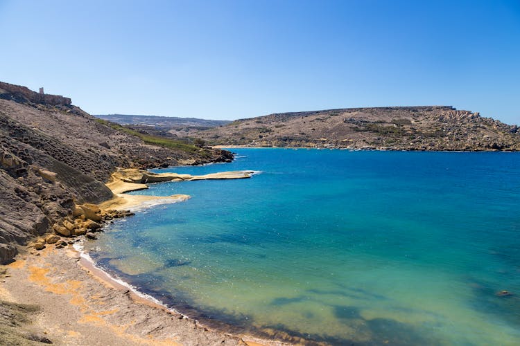 Photo of Bay of Gnejna, Manikata, Malta with blue sky.