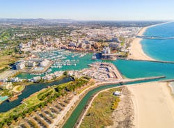 photo of an aerial view of wide sandy beach in touristic resorts of Quarteira and Vilamoura, Algarve, Portugal.