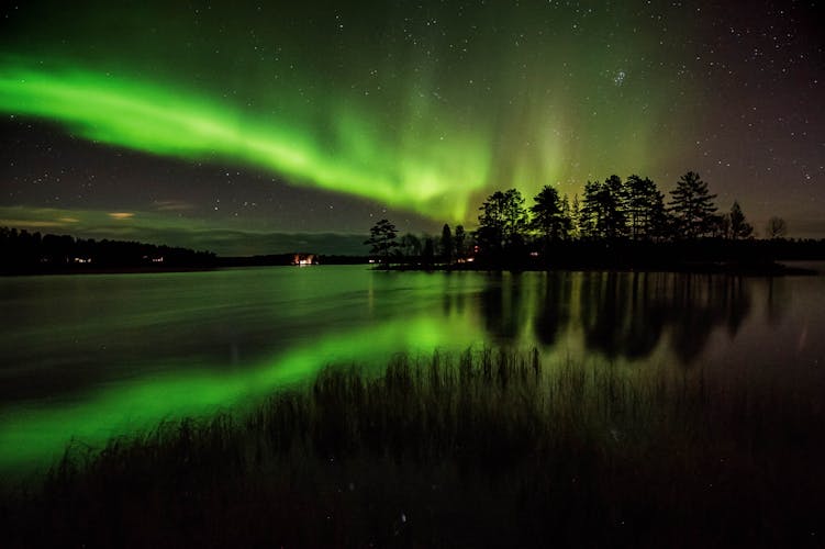 Photo of northern lights and it´s reflection in the lake in Kuusamo, Finland.