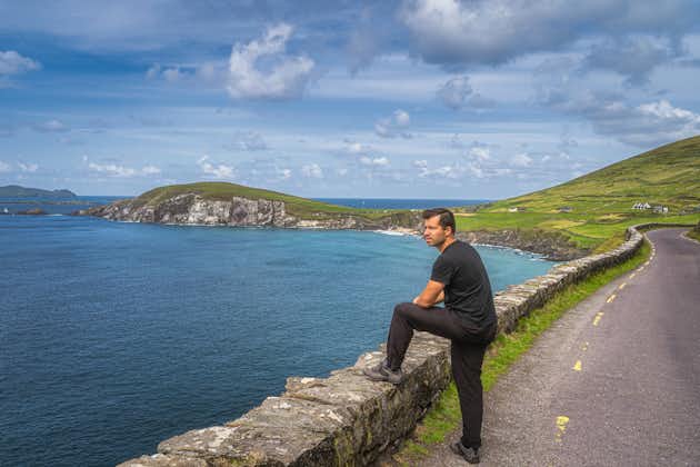 photo of Middle age man watching and admiring amazing view of Slea Head, Coumeenoole Beach and Dingle Peninsula, part of Wild Atlantic Way, Kerry, Ireland .