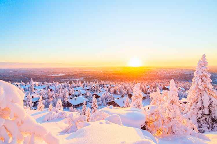 Photo of Stunning sunset view over wooden huts and snow covered trees in Kuusamo .