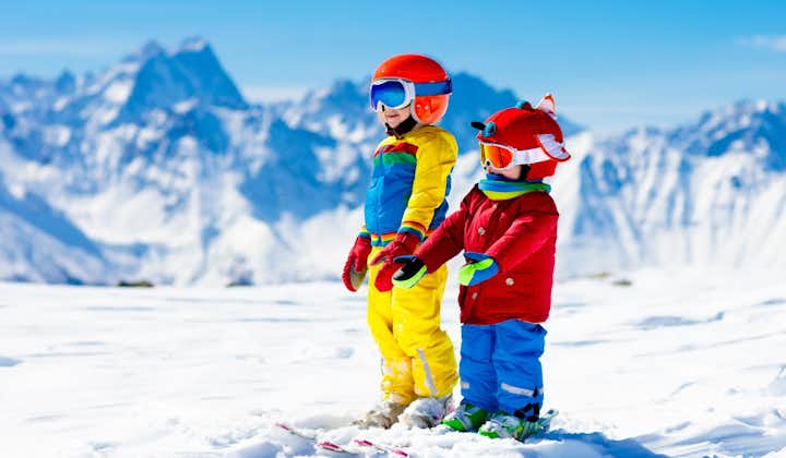 Photo of family Christmas vacation in the Alps. Children learn downhill skiing, Les Deux Alpes.