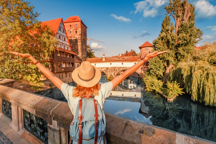 Photo of woman tourist enjoying sunset view of the old town of Nurnberg city and Pegnitz river.