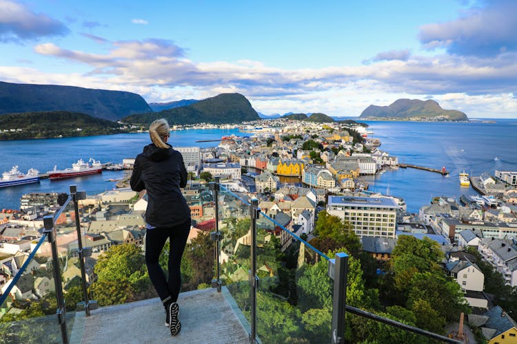 Blond woman enjoying aerial view of the colorful town of Alesund, Norway.