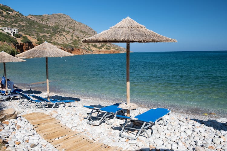 Photo of beautiful Plaka beach with is traditional blue table and chairs and the beach in Crete Greece.