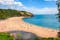 Photo of aerial view of sunny seascape with people enjoying the beach in Blackpool Sands, Devon, UK.